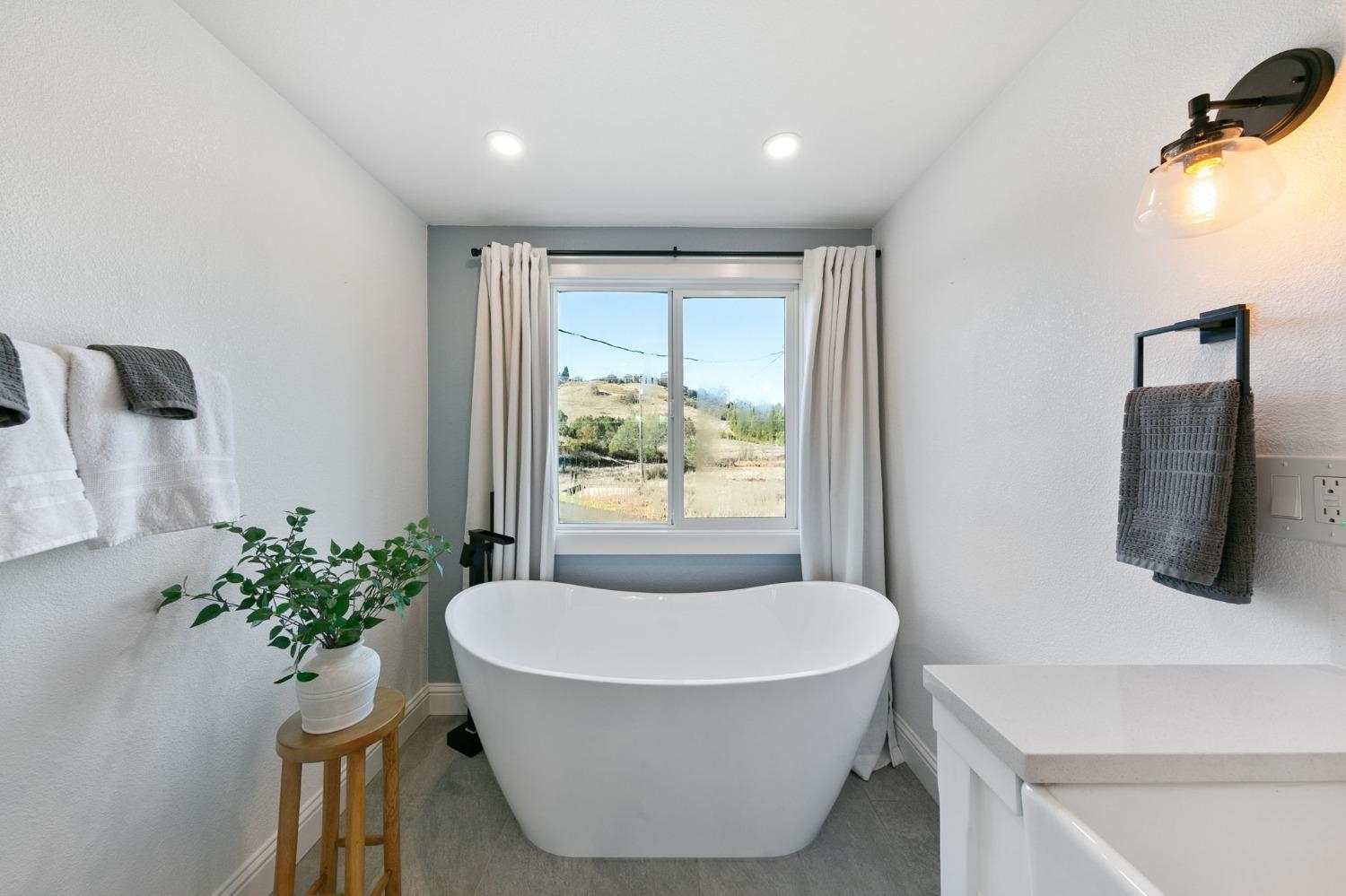 Modern freestanding soaking tub with hillside view